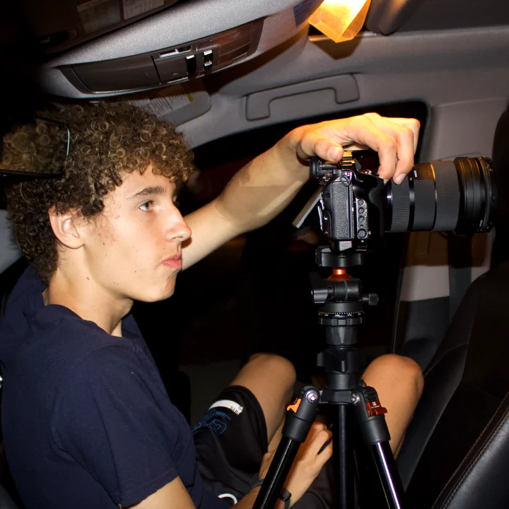 Devin Schlatter setting a camera on a tripod in the front seat of a car
